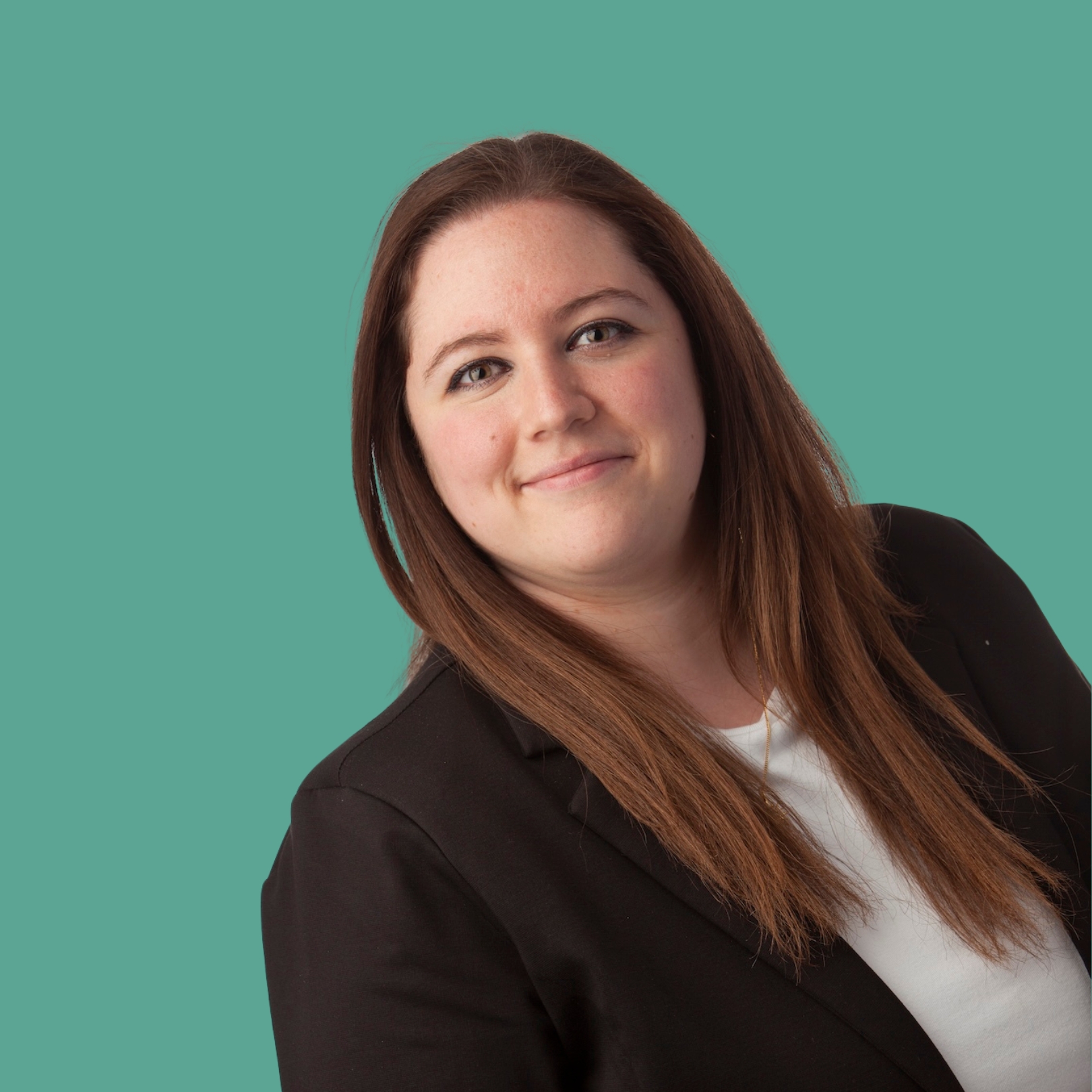 Porträt einer freundlichen, brünetten Frau, die ein weißes Shirt und einen schwarzen Blazer trägt. Der Hintergrund ist grün/türkis.