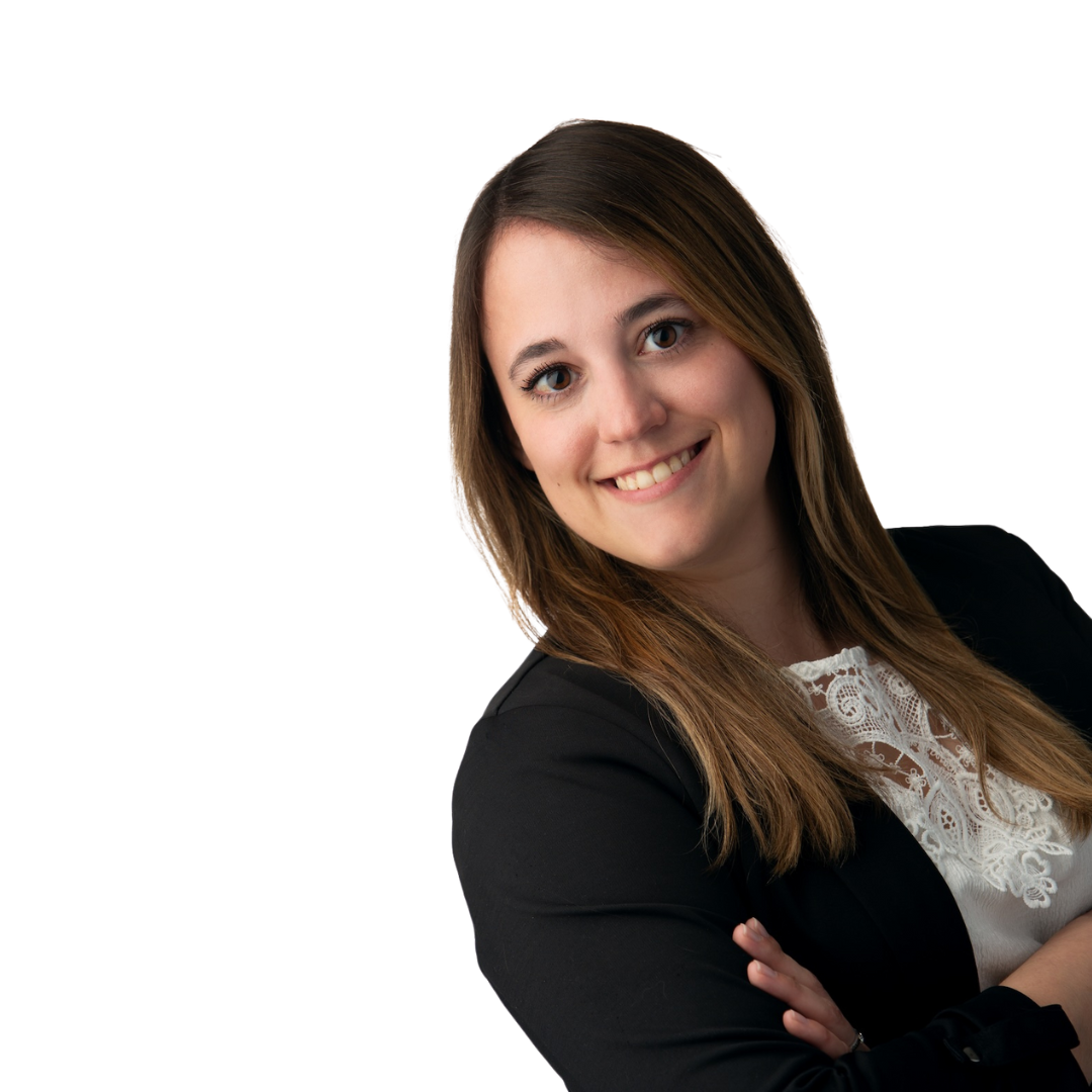 Porträt einer brünetten, freundlichen Frau, die mit verschränkten Armen lächelt.