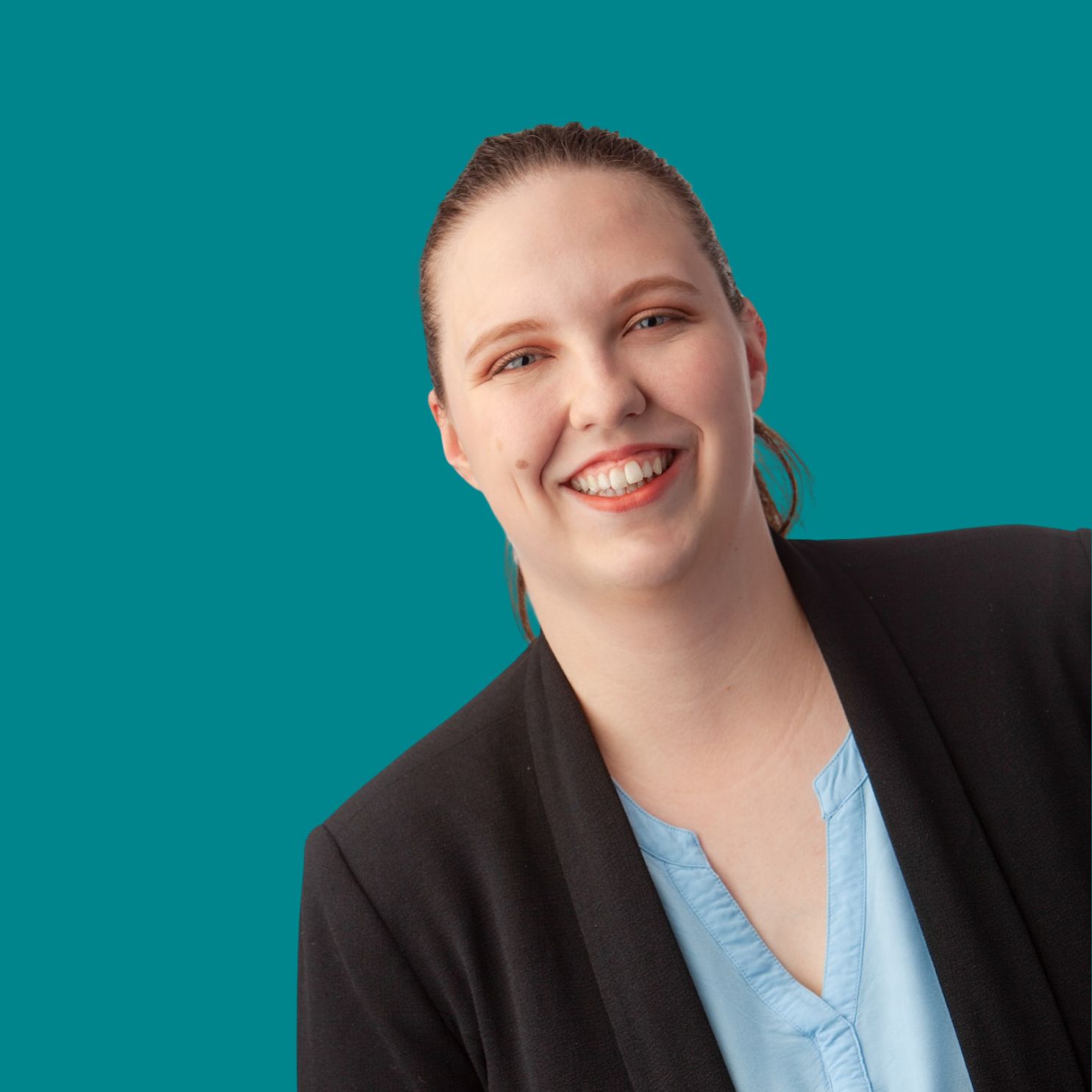 Porträt einer freundlichen Frau, die ein blaues Shirt und einen schwarzen Blazer trägt. Der Hintergrund ist türkis.